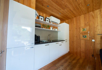 Kitchenette moderne avec meubles blancs et murs en bois au lodge Fred à De Wije Werelt, aux Pays-Bas.