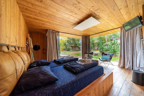 Fred lodge en De Wije Werelt, Países Bajos, dormitorio cálido de madera con vistas a la naturaleza exterior.
