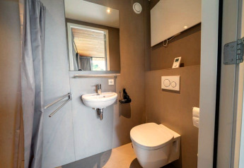 Modern bathroom at lodge Fred in De Wije Werelt, Netherlands, with wall-mounted toilet and small sink.