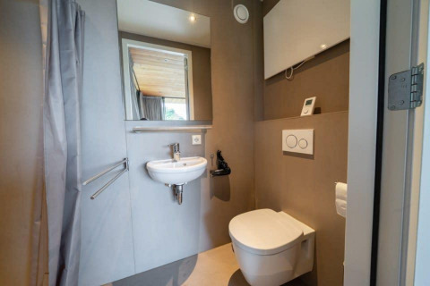Baño moderno en la cabaña Fred de De Wije Werelt, Países Bajos, con inodoro suspendido y lavabo pequeño.