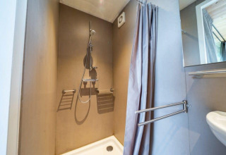 Ducha moderna con cortina en lodge Fred en De Wije Werelt, Países Bajos, equipada con barras de apoyo.