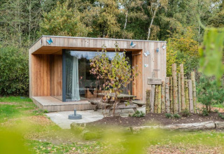 Cabane en bois nommée Fred à De Wije Werelt aux Pays-Bas, entourée de verdure et d’arbres.