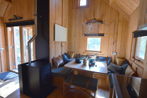 Cozy wooden tiny house interior in the Treehouse at De Wije Werelt, Netherlands, featuring a dining nook.