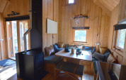 Hyggelig indretning i træ i et tiny house, Treehouse ved De Wije Werelt, Holland, med spisehjørne og brændeovn.