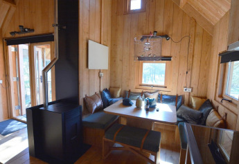 Hyggelig indretning i træ i et tiny house, Treehouse ved De Wije Werelt, Holland, med spisehjørne og brændeovn.