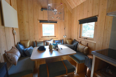 Acogedor interior de pequeña casa en el Treehouse de De Wije Werelt, Países Bajos, con bancos de esquina.