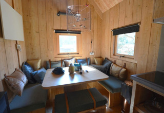 Cozy tiny house interior at Treehouse, De Wije Werelt, Netherlands, with wooden walls and corner seating.