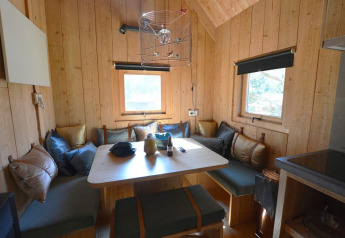 Gemütlicher Innenraum eines kleinen Baumhauses in De Wije Werelt, Niederlande, mit Holzwänden und Sitzbank.