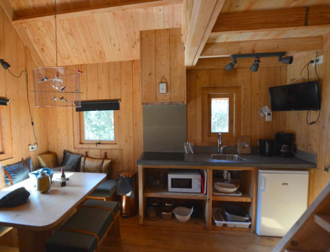 Knus interieur van een boomhut bij De Wije Werelt in Nederland met keuken en eethoek in beeld.