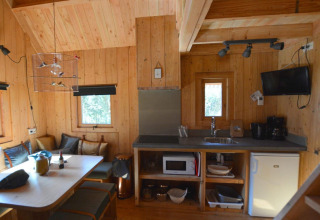 Knus interieur van een boomhut bij De Wije Werelt in Nederland met keuken en eethoek in beeld.