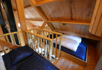 Slaapruimte op de mezzanine met hout binnenin Treehouse bij De Wije Werelt, een tiny house in Nederland.
