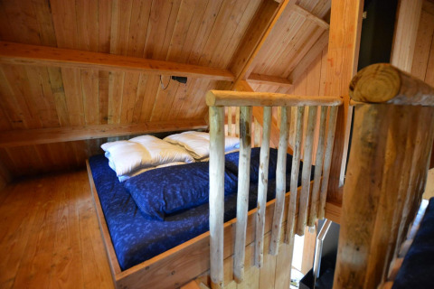 Knus loftbed met blau beddengoed in de Treehouse bij De Wije Werelt tiny house, Nederland.