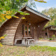 Billede af det unikke tiny house Geurt i træ, omgivet af natur og blade, ideelt til afslapning.