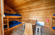 Intérieur de la tiny house Geurt à De Wije Werelt, Pays-Bas, avec lits superposés, table et tabourets.