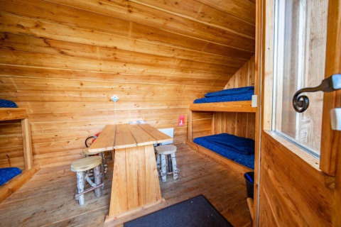 Interior de la tiny house Geurt en De Wije Werelt, Países Bajos, con literas y paredes de madera.
