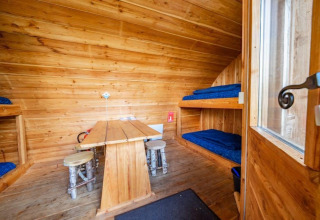 Interior de la tiny house Geurt en De Wije Werelt, Países Bajos, con literas y paredes de madera.