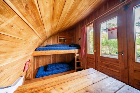 Vista interior de la tiny house Geurt en De Wije Werelt, Países Bajos, con literas y decoración de madera.