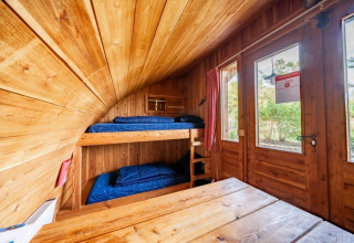 Vista interior de la tiny house Geurt en De Wije Werelt, Países Bajos, con literas y decoración de madera.