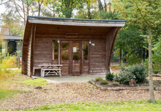 Pequeña casa de madera llamada Geurt en De Wije Werelt, rodeada de árboles y naturaleza en Países Bajos.