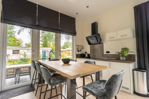 Moderne keuken en eethoek in Just Nature-lodge bij De Wije Werelt, tuinzicht door grote ramen.