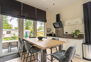 Moderne keuken en eethoek in Just Nature-lodge bij De Wije Werelt, tuinzicht door grote ramen.