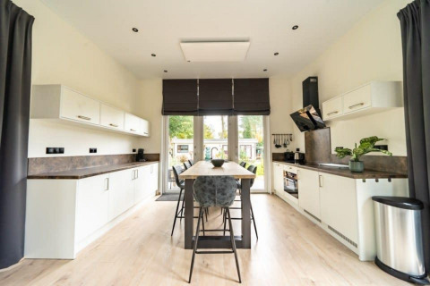Intérieur de cuisine moderne au lodge Just Nature à De Wije Werelt, Pays-Bas, avec îlot central et décor lumineux.