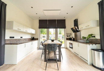 Moderne Kücheninnenraum in der Just Nature Lodge im De Wije Werelt, Niederlande, mit Essbereich und viel Licht.