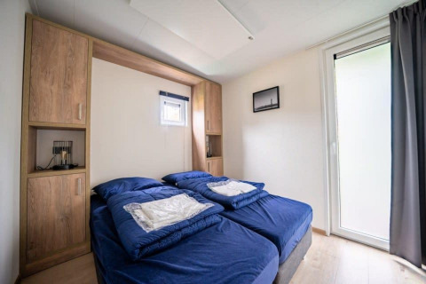 Camera da letto della lodge Just Nature a De Wije Werelt, Paesi Bassi, con due letti singoli blu.
