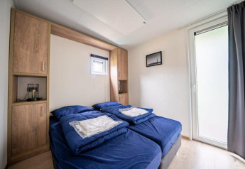 Soveværelse i Just Nature-lodge på De Wije Werelt i Holland med to enkeltsenge og blå sengetøj.