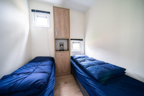 Lichte kamer bij Just Nature, De Wije Werelt, Nederland, met twee eenpersoonsbedden en blauwe lakens.