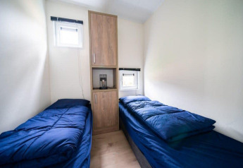 Helles Zimmer im Just Nature, De Wije Werelt, Niederlande, mit zwei Einzelbetten und blauer Bettwäsche.