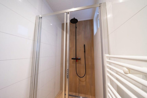 Ducha moderna en Just Nature, De Wije Werelt, Países Bajos, con puerta de vidrio y rociador de lluvia.