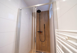 Ducha moderna en Just Nature, De Wije Werelt, Países Bajos, con puerta de vidrio y rociador de lluvia.