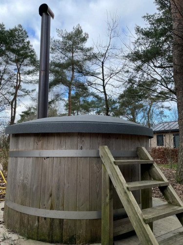 Outdoor wooden hot tub with chimney and stairs at Pavilion Hottub, De Wije Werelt in the Netherlands.