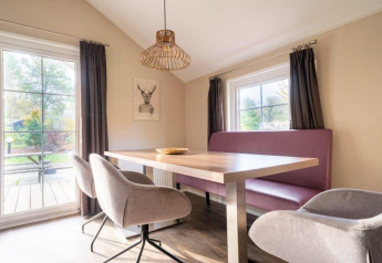 Essbereich in der Boslodge bei De Wije Werelt, Niederlande. Helles Zimmer mit Tisch, Stühlen und großen Fenstern.