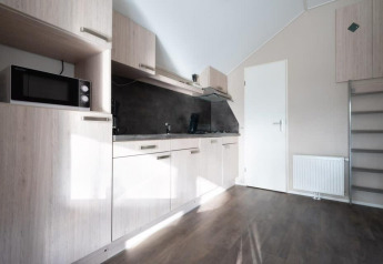Moderne kitchenette met houtkleurige kasten in de Boslodge op De Wije Werelt, Nederland.