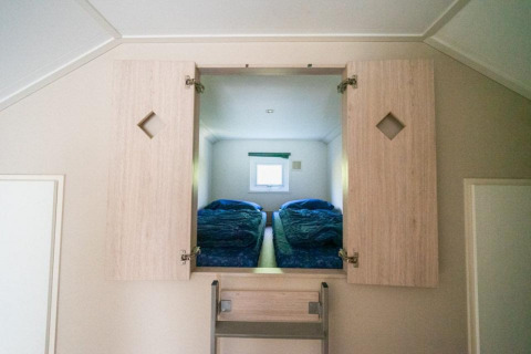 Entrada a dormitorio con dos camas a través de un armario en Boslodge de De Wije Werelt, Países Bajos.