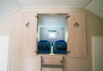 Eingang zu einem Schlafzimmer mit zwei Betten durch einen Schrank in der Boslodge, De Wije Werelt, Niederlande.
