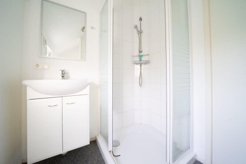 Helles Badezimmer mit Dusche und weißem Waschbecken in der Boslodge bei De Wije Werelt, Niederlande.