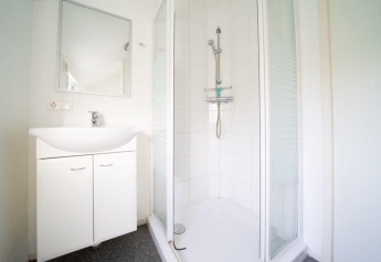 Helles Badezimmer mit Dusche und weißem Waschbecken in der Boslodge bei De Wije Werelt, Niederlande.
