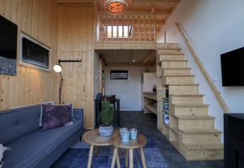 Tiny house moderne avec murs en bois, mezzanine, escalier, salon et cuisine à Buitenhuizen, Pays-Bas.