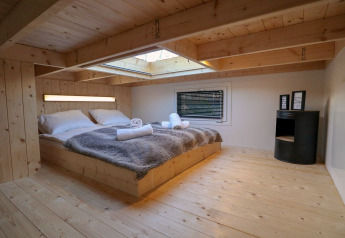 Camera da letto in legno presso Tiny House at Buitenhuizen, Olanda, con lucernario e arredamento accogliente.