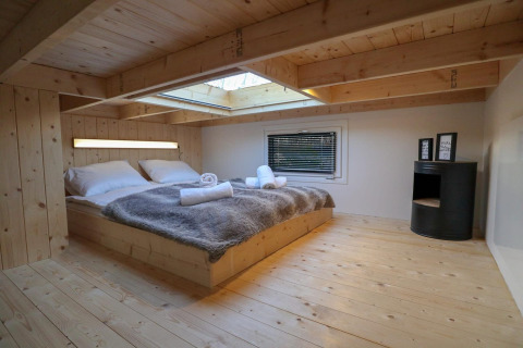 Schlafzimmer im Tiny House at Buitenhuizen in den Niederlanden mit Holzverkleidung und Oberlichtfenster.