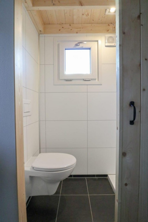 Baño moderno y pequeño en Tiny House at Buitenhuizen, Países Bajos, con inodoro suspendido y ventana.