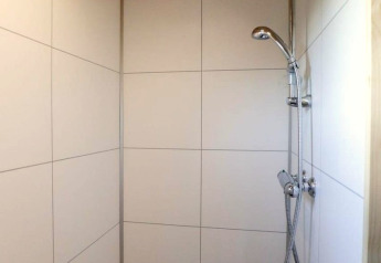 Doccia con soffitto in legno e piastrelle bianche nel Tiny House at Buitenhuizen, Paesi Bassi.