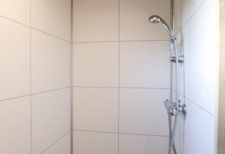 Doccia con soffitto in legno e piastrelle bianche nel Tiny House at Buitenhuizen, Paesi Bassi.