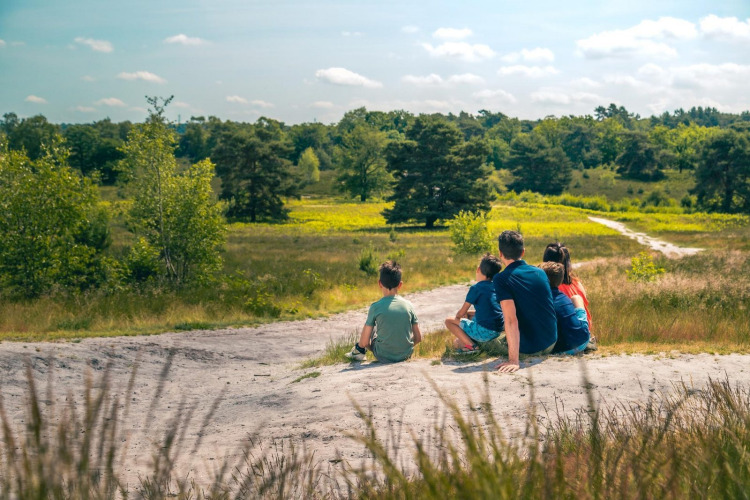 Una familia se sienta junta disfrutando de la naturaleza en su alojamiento glamping, rodeada de campo.