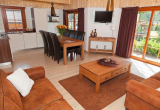 Interno lodge moderno con mobili in legno, divani in pelle e grandi finestre nei Paesi Bassi.