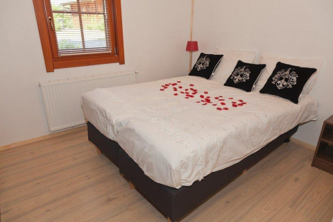 Acogedor dormitorio en Boekhorst Royal + Sauna, Brunssummerheide, Países Bajos, con pétalos de rosa en la cama.
