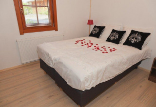 Gezellige slaapkamer bij Boekhorst Royal + Sauna, Brunssummerheide, Nederland, met rozenblaadjes op het bed.